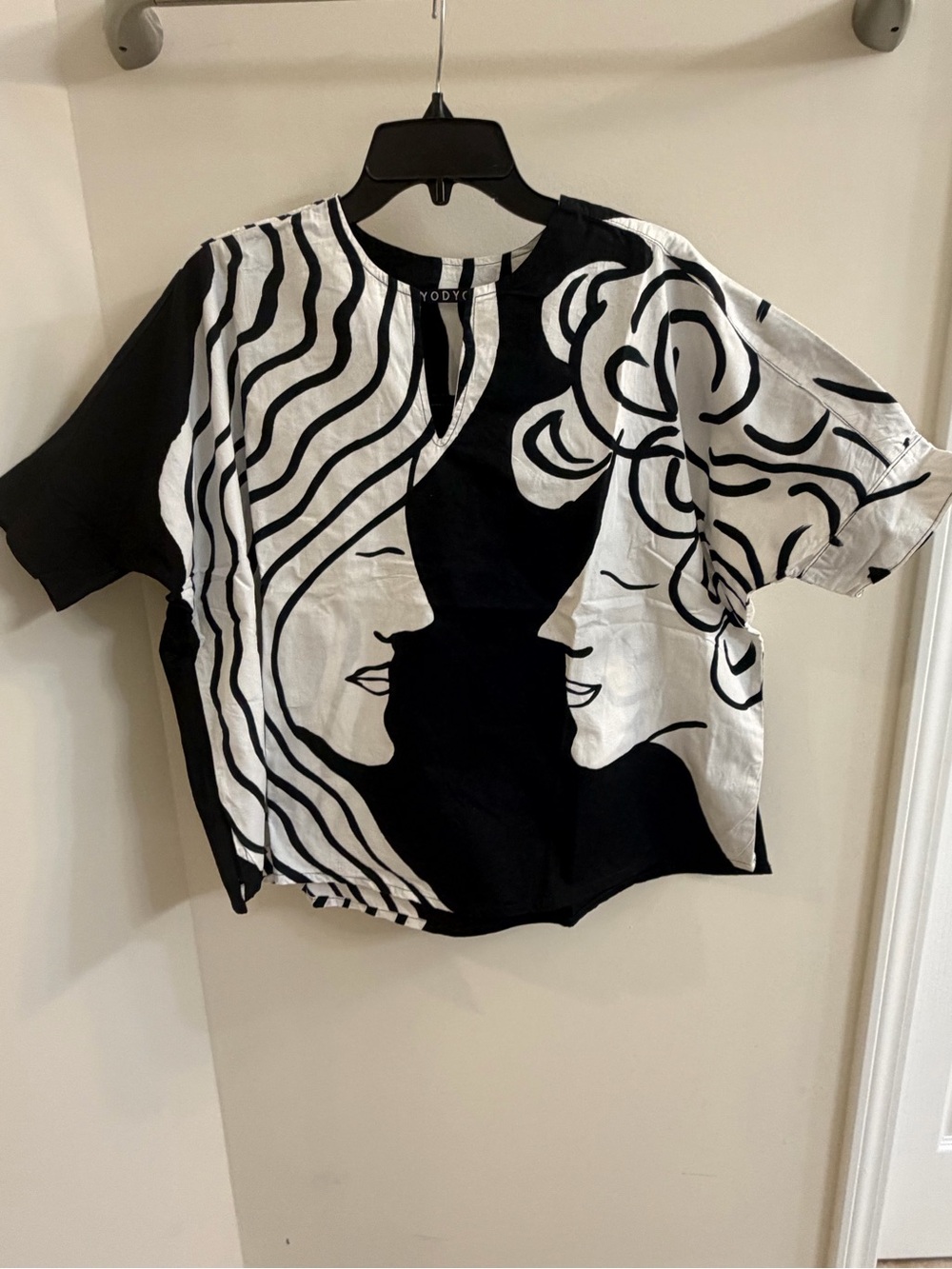 black-and-white short-sleeve top featuring an abstract continuous-line face